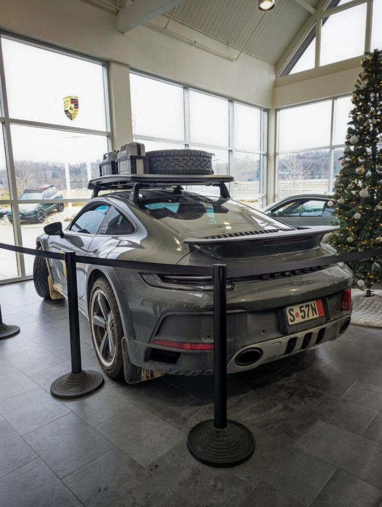 A gray Porsche 911 Dakar parked inside a showroom near Christmas decorations.