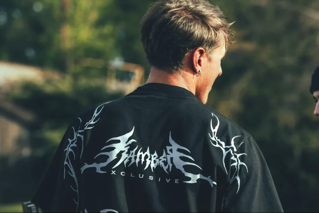 Back view of a person wearing a black shirt with silver graphics, outdoors.