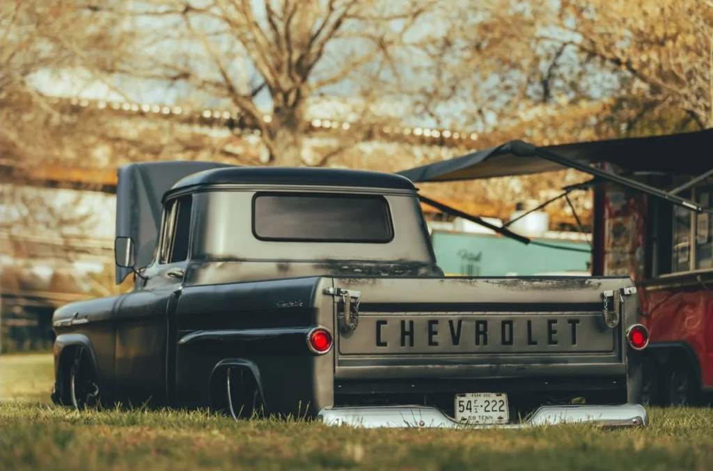 Black Chevrolet pickup truck parked on grass with trees in the background.