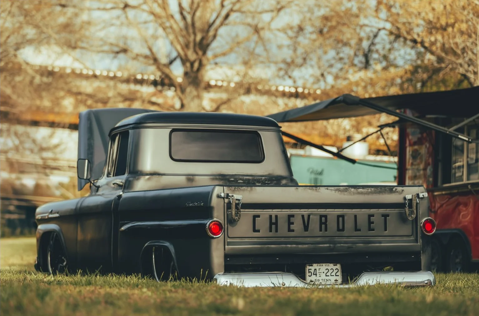Black Chevrolet pickup truck parked on grass with trees in the background.