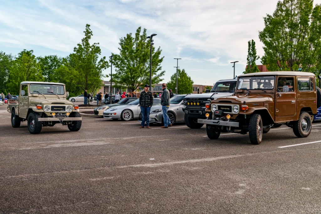 Two vintage Toyota Land Cruisers a beige pickup on the left and a brown Land Cruiser on the right