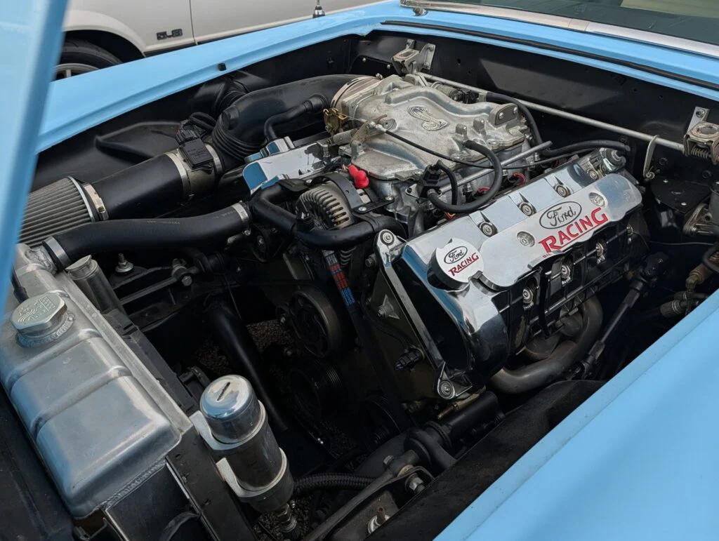 Engine bay featuring a Ford Racing engine with chrome details in a blue vehicle.