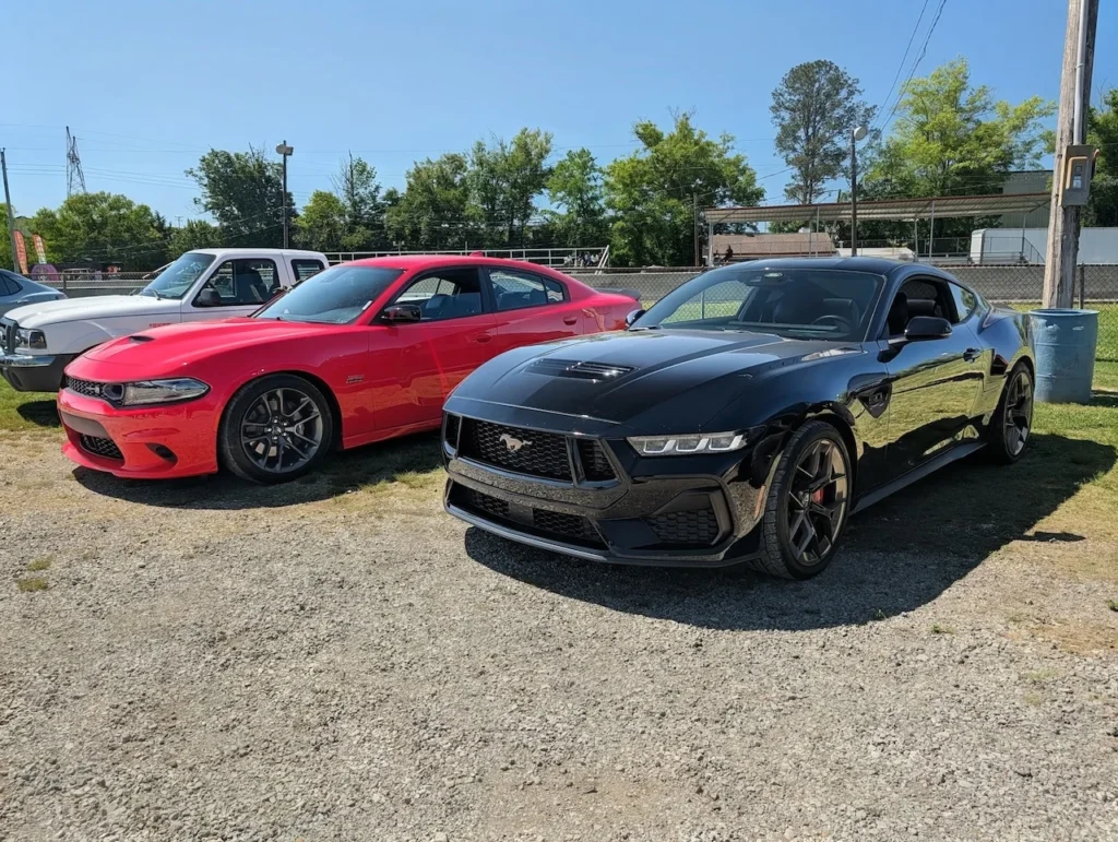 A red Dodge Charger and a black Ford Mustang parked side by side in an outdoor setting.