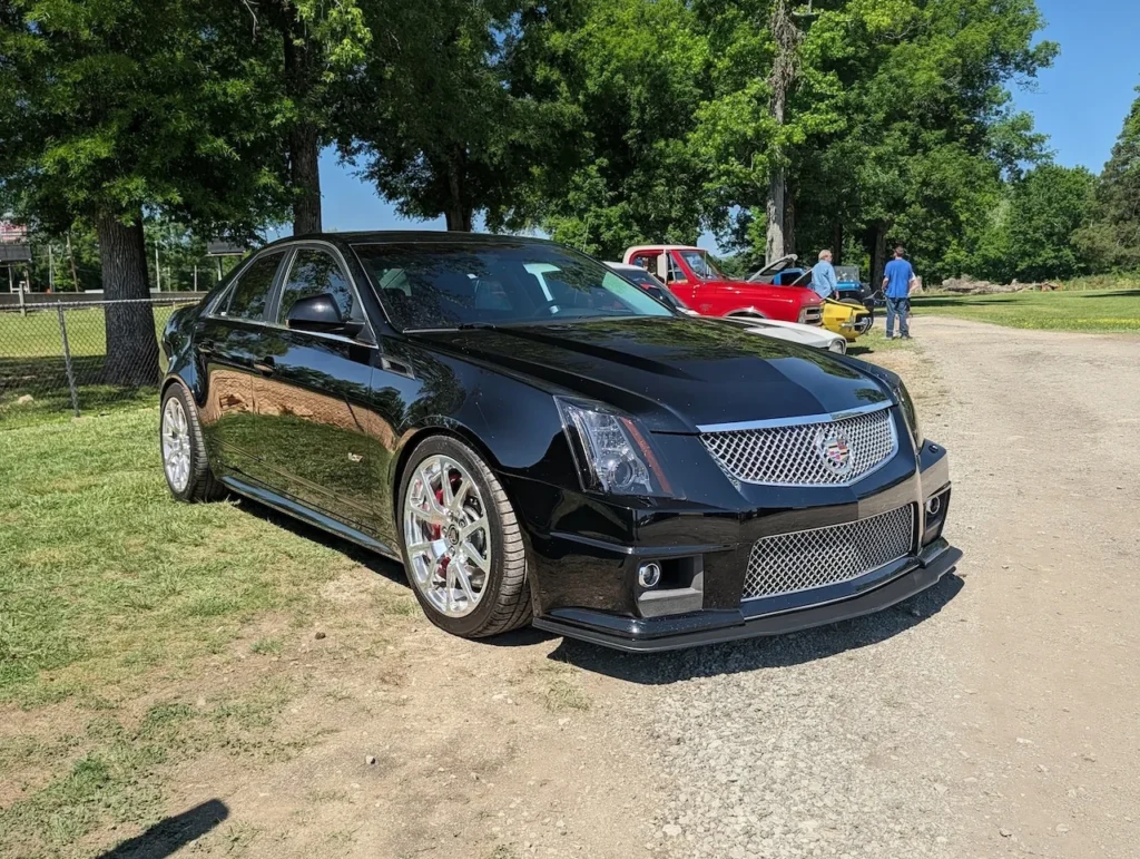 A black Cadillac CTS-V parked on grass with trees in the background.