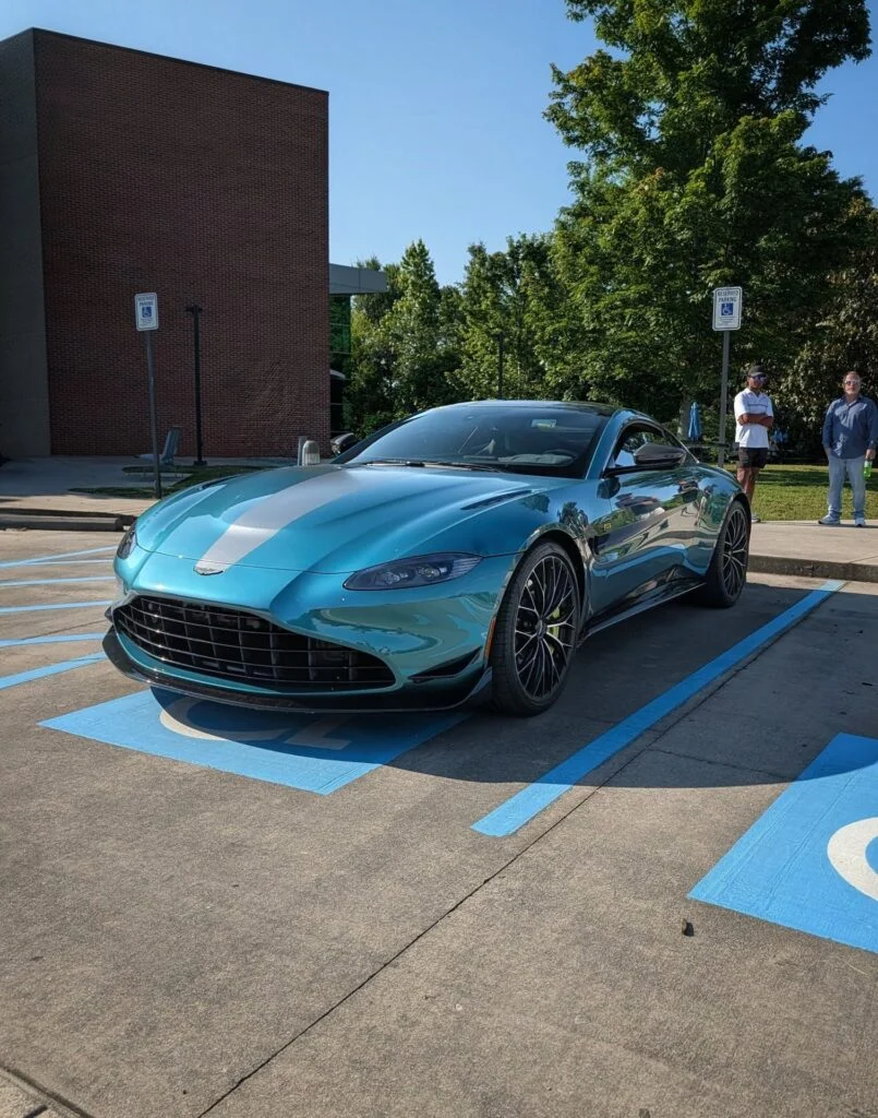 Aston Martin Vantage F1 Edition parked in a handicapped space outside near a brick building with two people standing in the background