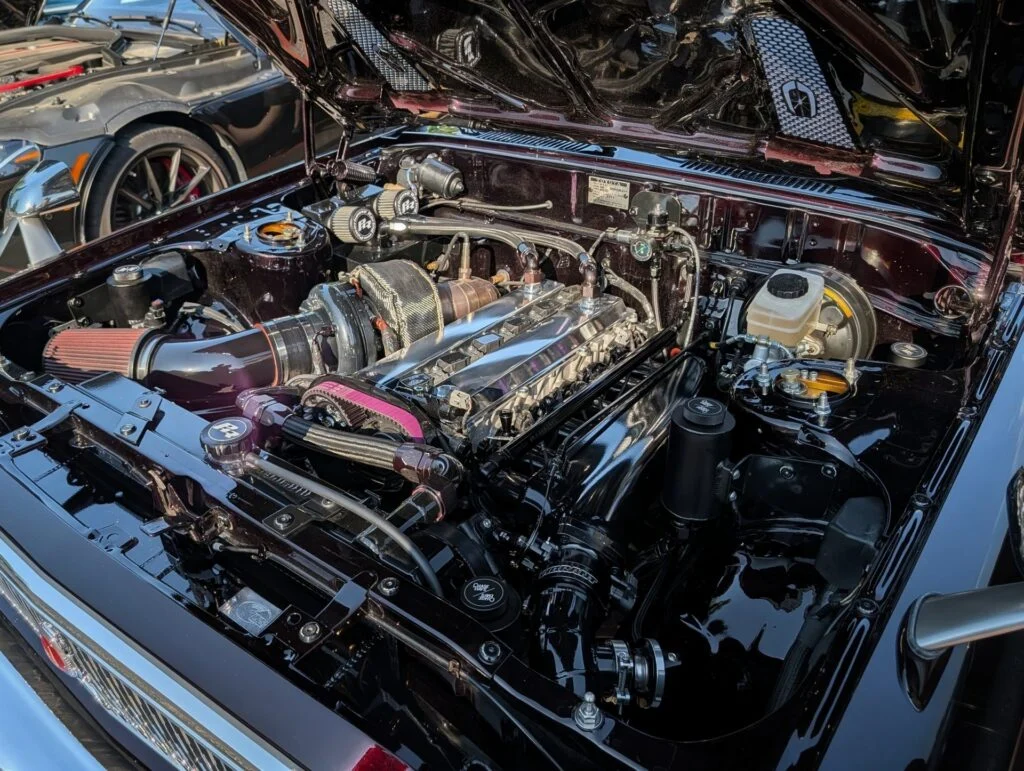 Detailed view of a polished Toyota Cressida engine bay with visible turbocharger and components inside a vehicle at a car event.