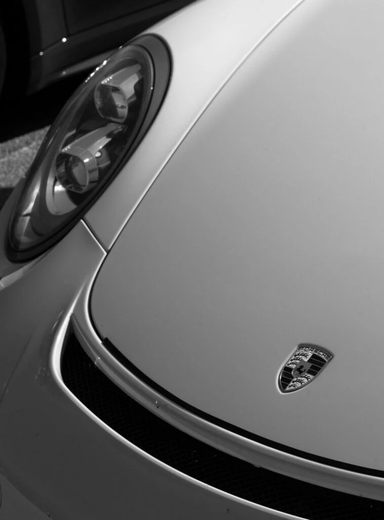 Close-up of a Porsche 911 front hood and headlight with the Porsche badge visible