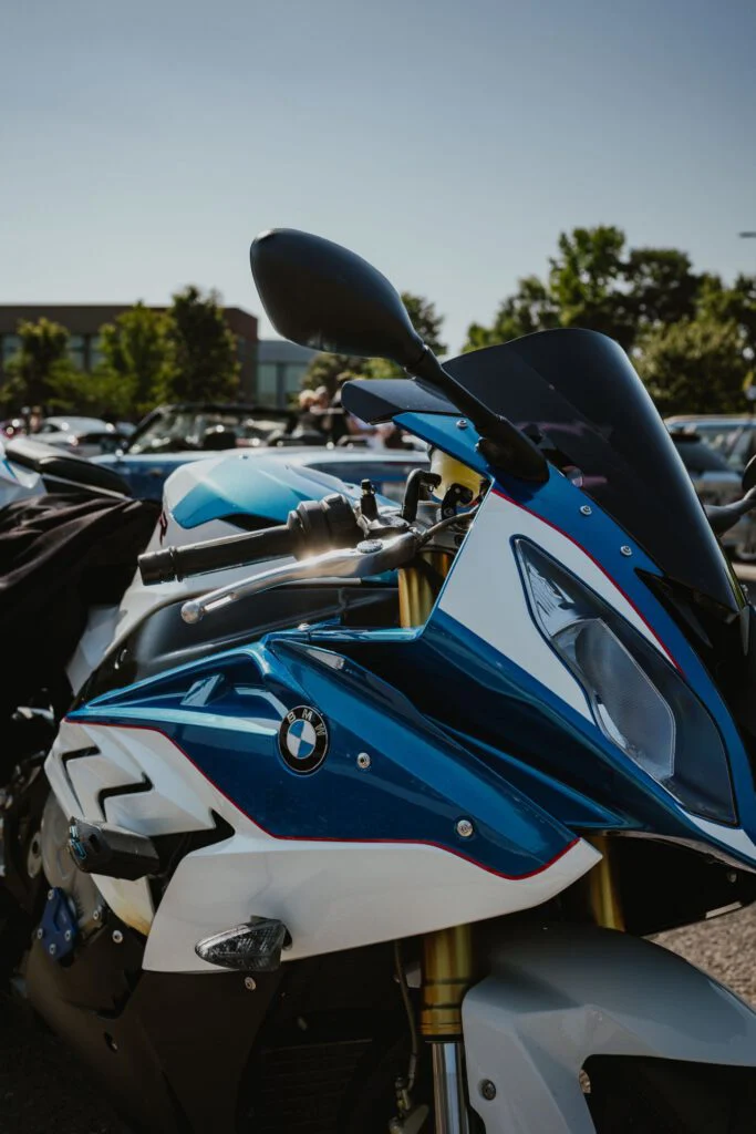 Blue and white BMW motorcycle parked outdoors with other vehicles and trees in background
