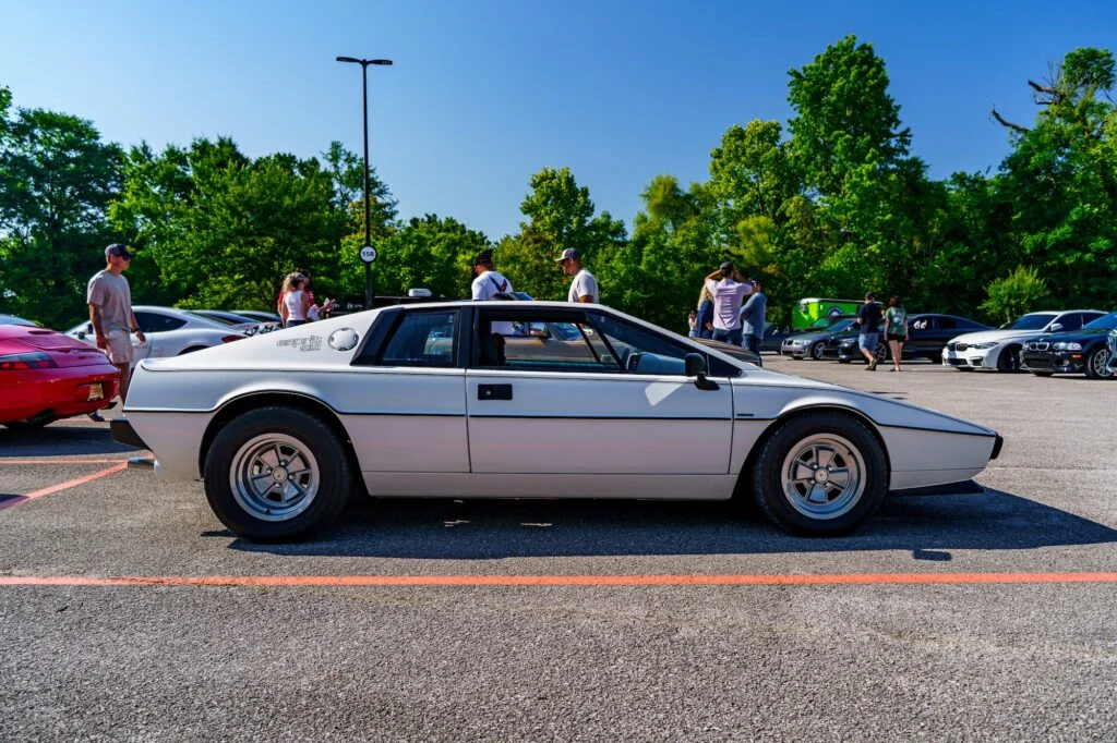 White Lotus Esprit S2 parked in a lot with people and other cars in the background under clear blue sky