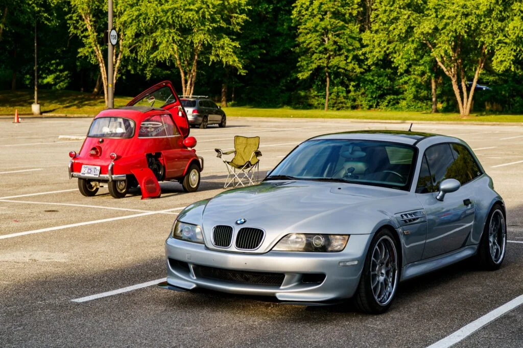 Silver BMW Z3 coupe front quarter with red BMW Isetta bubble car with open door in parking lot