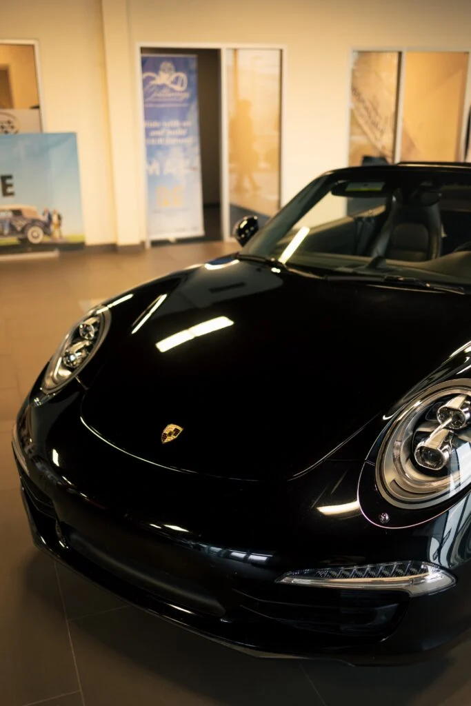 Front section of a black Porsche with visible headlights and badge indoors