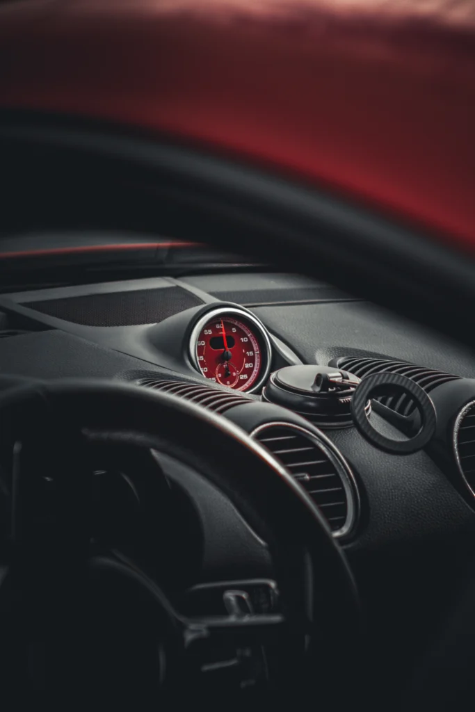 Close-up view of a red dashboard clock and black dashboard vents inside a car