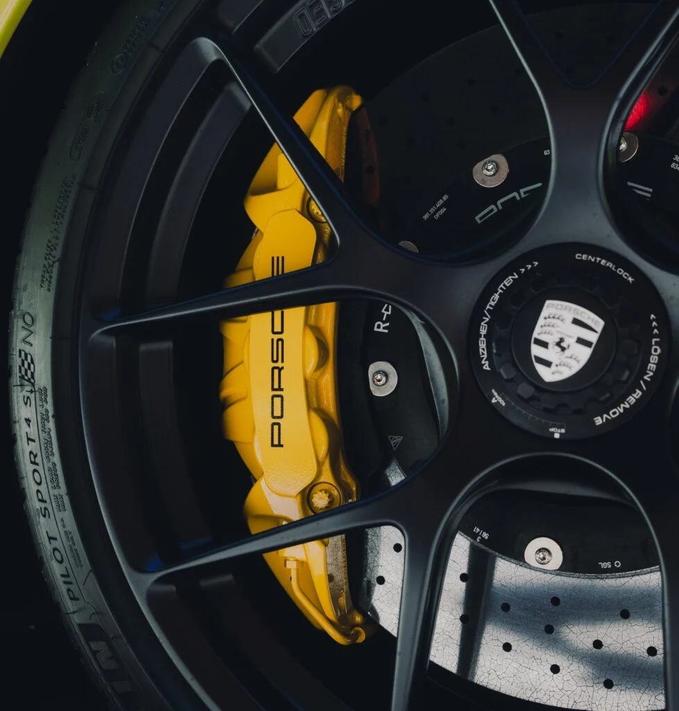 Close-up of a black wheel featuring a prominent yellow Porsche brake caliper.