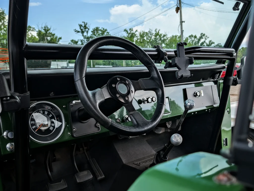 Interior view of a Ford Bronco dashboard and steering wheel with gear shifters and a rear roll bar visible