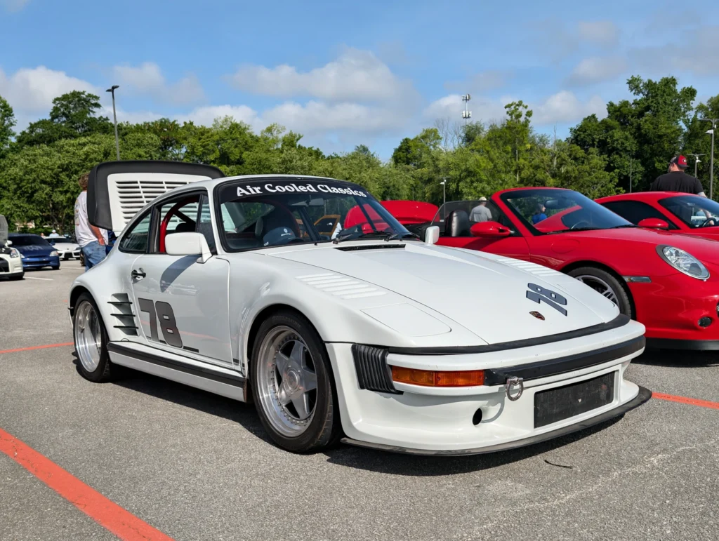 White Porsche 911 Slantnose with 'Air Cooled Classics' decal on the windshield and hood open at an outdoor car event
