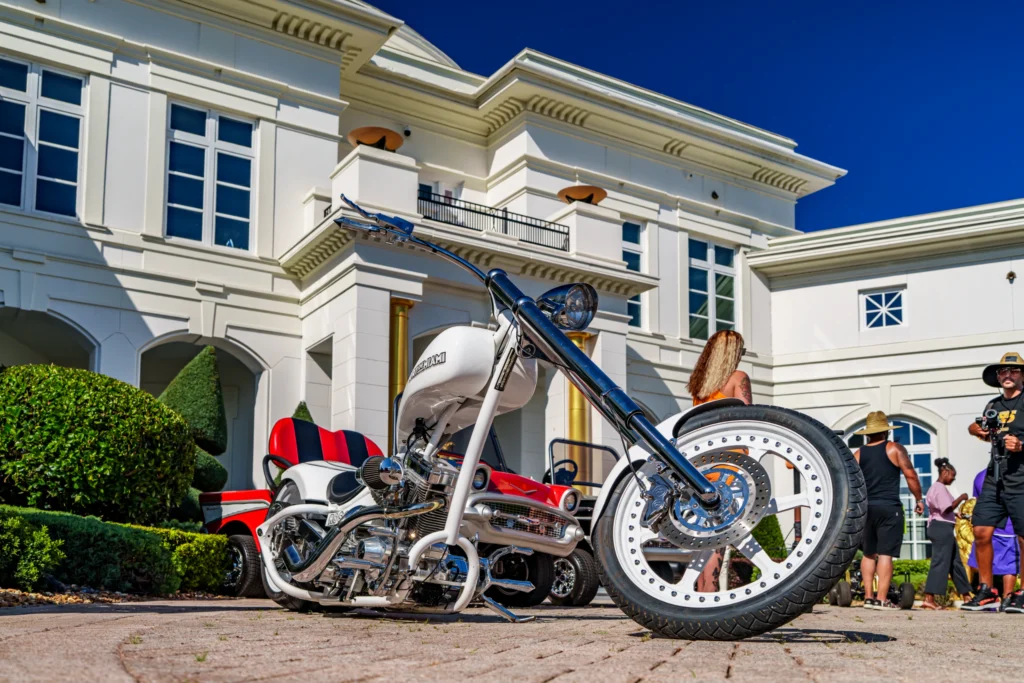 White and red trike motorcycle parked outside a large white building with people in the background
