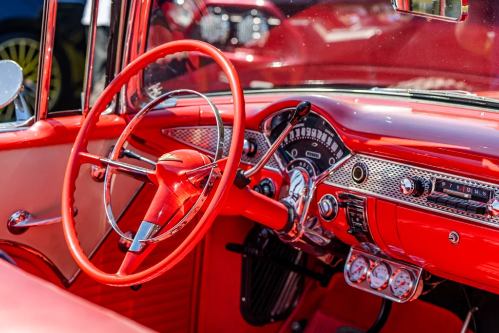 Red Chevrolet Bel Air interior showing steering wheel, dashboard, and gauges