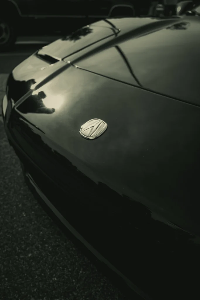 Close-up of Acura hood with badge and reflections of nearby objects
