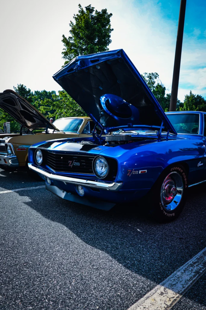 Blue Chevrolet Camaro Z/28 with hood open at outdoor car show