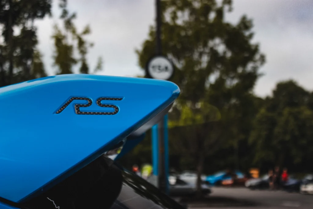 Blue Ford Focus RS rear wing with RS badge in outdoor setting with trees and parked cars
