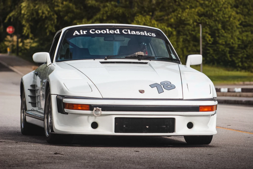 White Porsche 911 with Air Cooled Classics decal on windshield and number 78 on hood parked on street