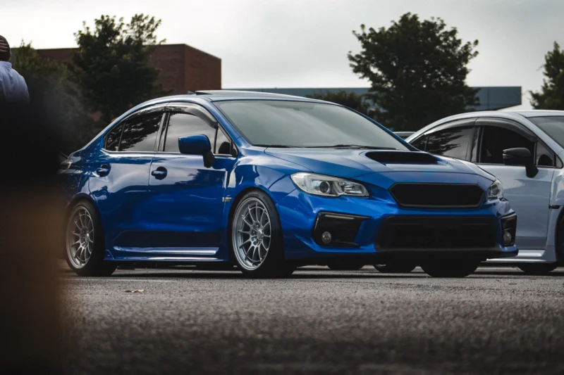 Blue Subaru WRX parked outdoors with trees and another car in the background