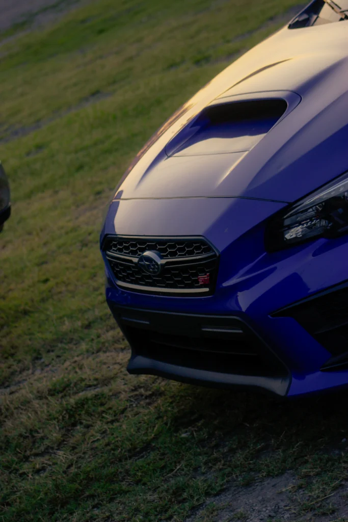 Blue Subaru WRX STI front hood and grille parked on grass