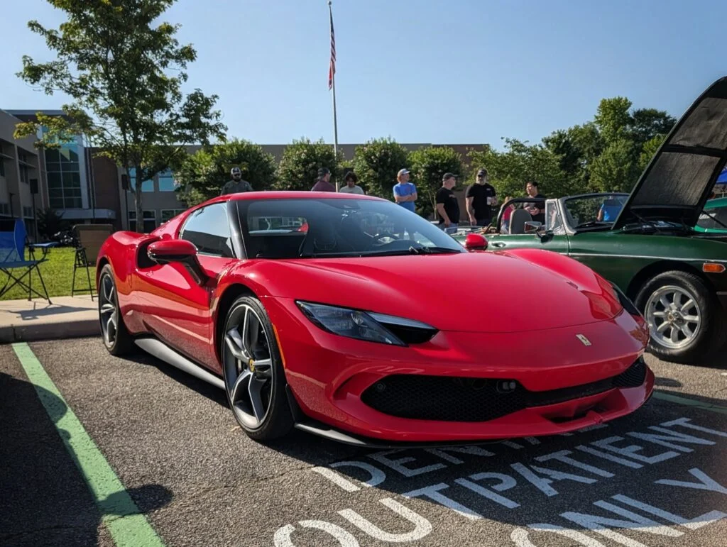 Red Ferrari 296 parked in a reserved parking space at an outdoor car event with people and trees in the background