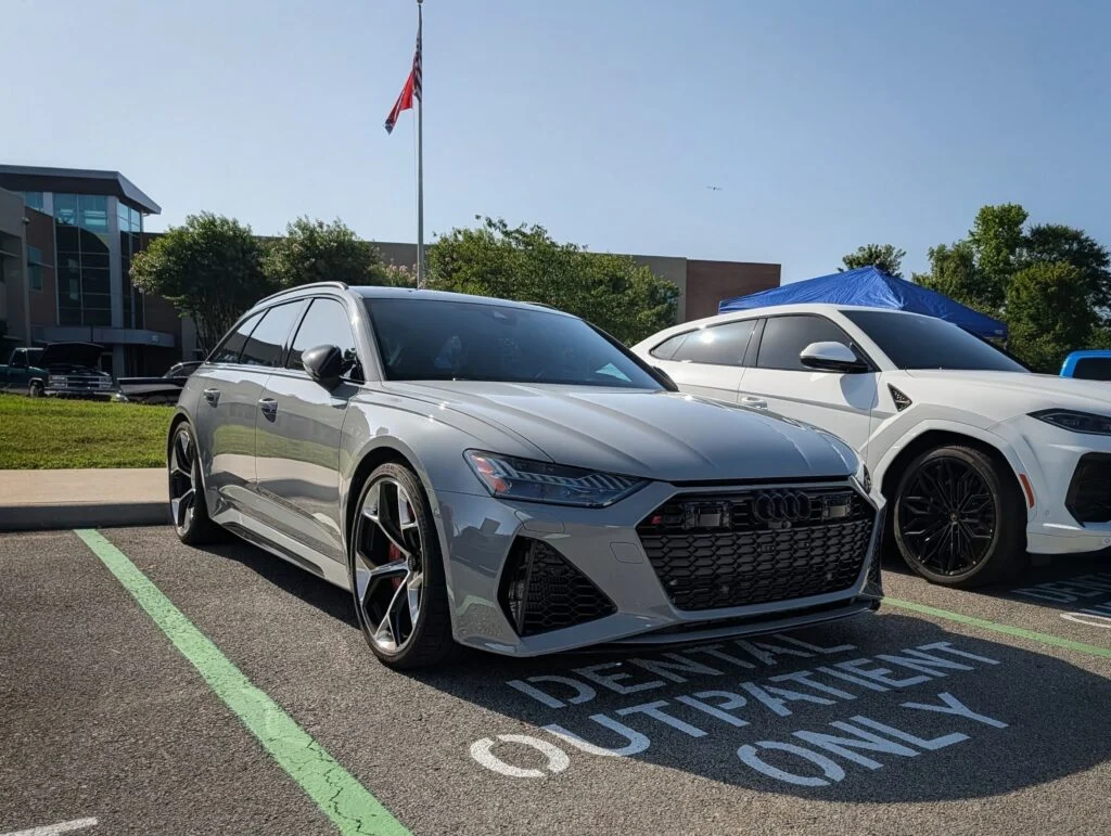 Silver Audi RS 6 Avant parked outdoors beside a white SUV under clear daylight