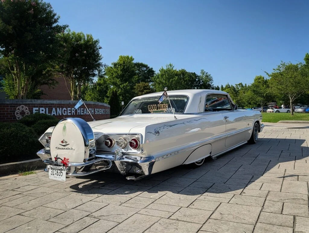 White Chevrolet Impala parked near a brick sign for Erlanger Health Science Center on a sunny day