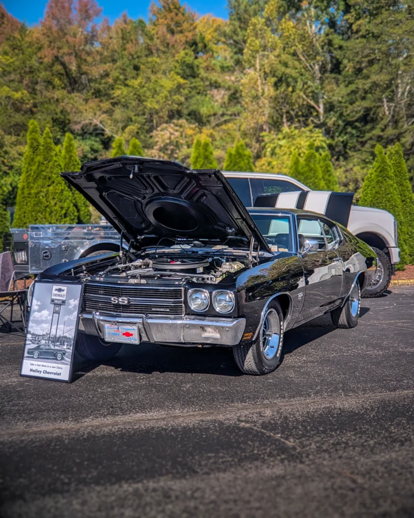 Black Chevrolet Chevelle SS with open hood parked outdoors with trees in background