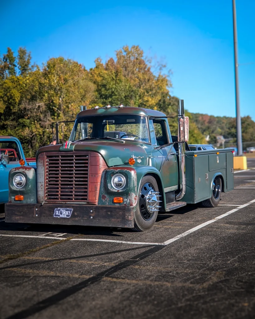 Green International Harvester truck parked in a lot with trees and blue sky in the background