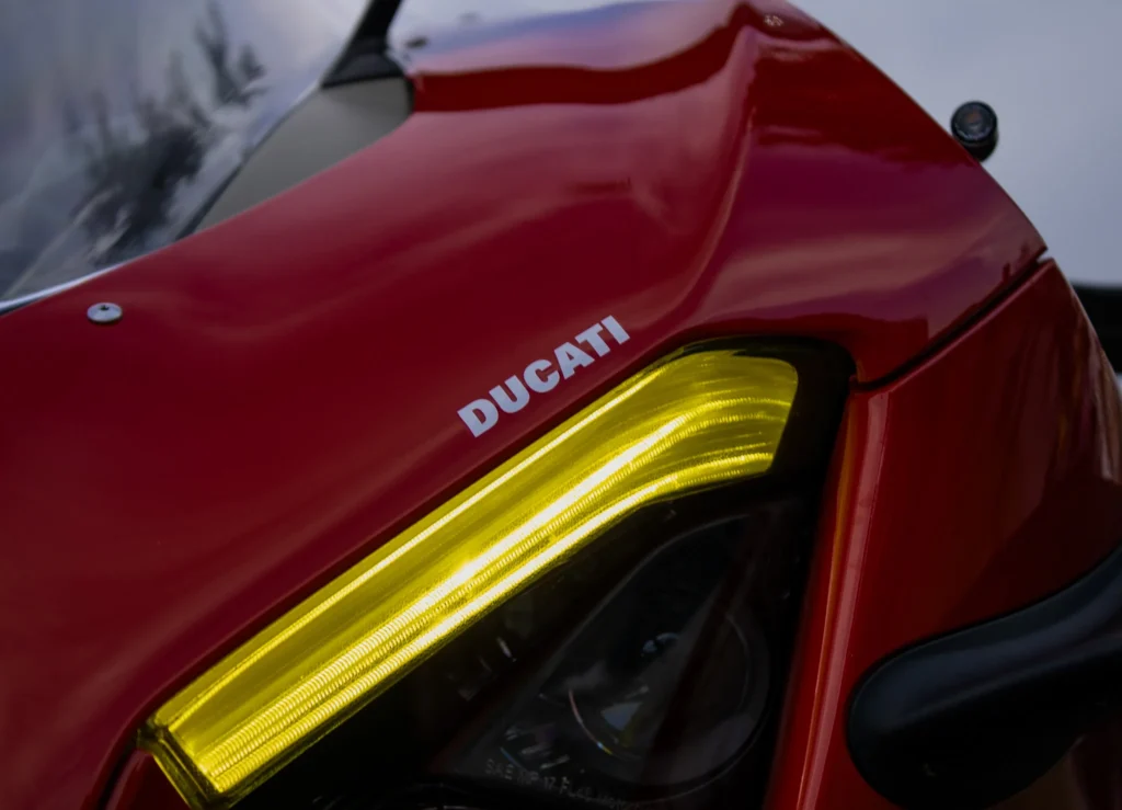 Close-up of yellow headlight and red bodywork with Ducati logo on a motorcycle