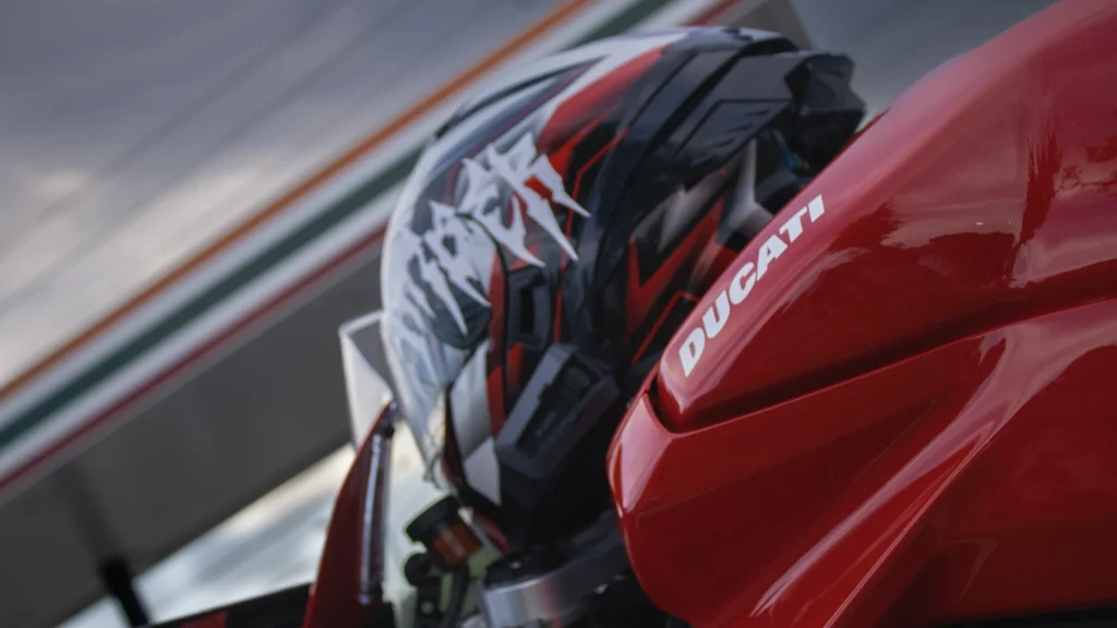 Red Ducati motorcycle fuel tank and a red and black motorcycle helmet with graphic design