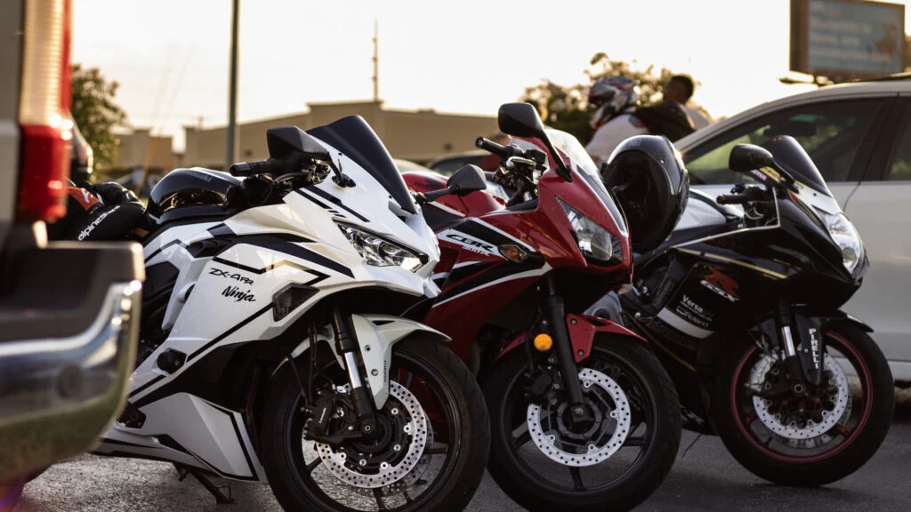 Three sport motorcycles including a white Kawasaki Ninja ZX-4R, a red Honda CBR, and a black Suzuki GSX-R parked side by side
