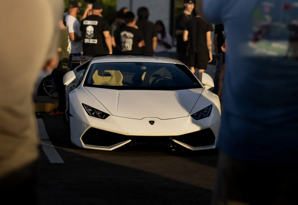White Lamborghini Huracán with yellow seats parked outside surrounded by people at a car event