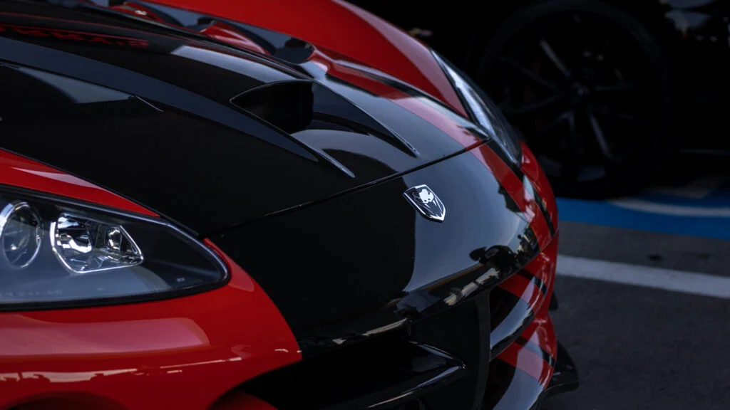 Close-up of black and red Dodge SRT Viper GTS hood and headlight with emblem visible, parked outdoors on asphalt.