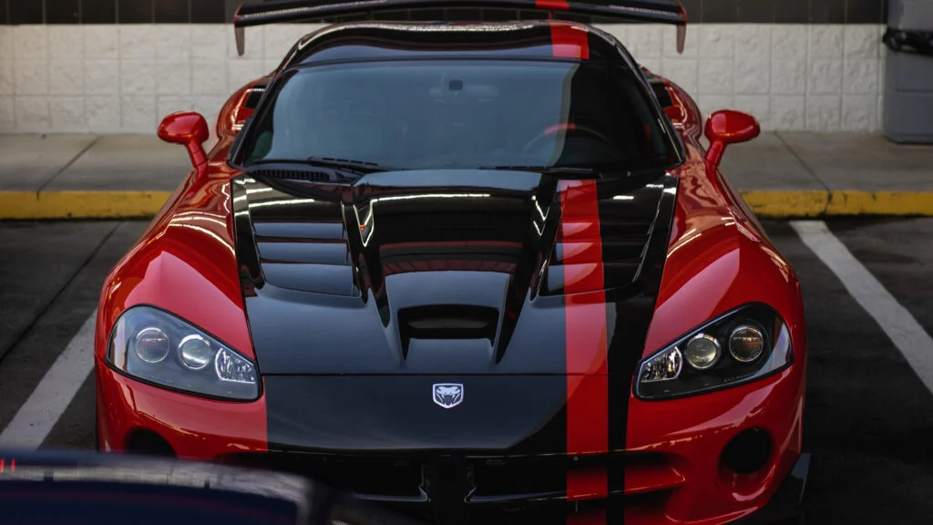 Red Dodge SRT Viper GTS with black and red racing stripes, front view in a parking lot