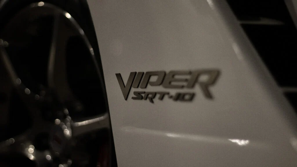 Close-up view of SRT-10 Viper badge on white vehicle near wheel