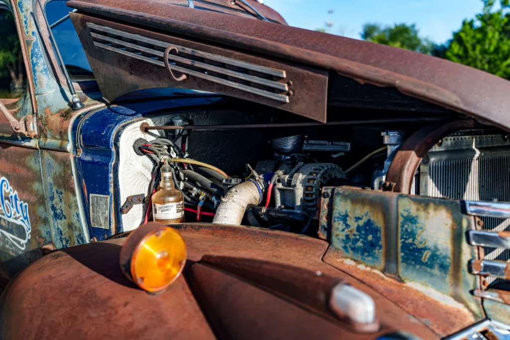 Rusty blue and brown 46 Chevrolet truck with its hood open showing engine components
