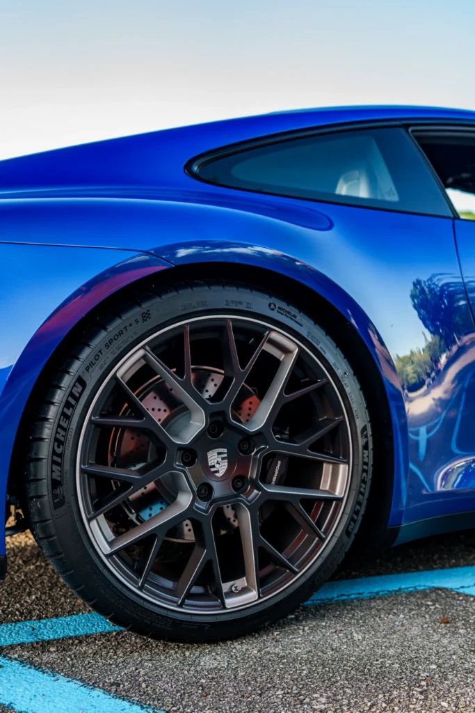 Rear side view of a blue Porsche showing the wheel and part of the rear window.