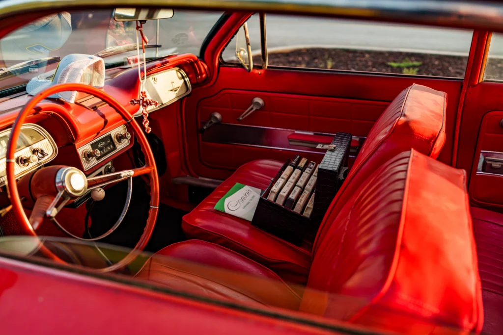 Interior of a red vintage Chevrolet Corvair Monza featuring red seats, dashboard, and steering wheel