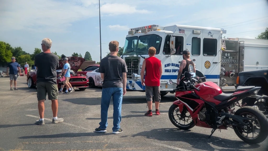 Red Honda sport motorcycle parked near a white Red Bank Fire Department fire truck with people gathered around in a parking l