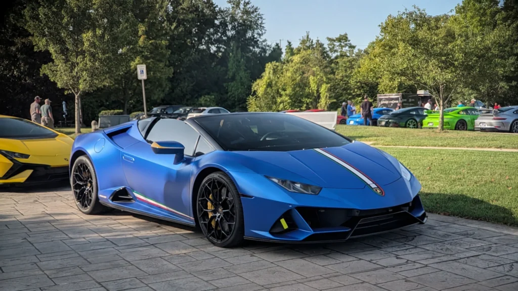 Blue Lamborghini Huracán Performante Spyder parked with yellow Lamborghini and other cars at an outdoor event with people and