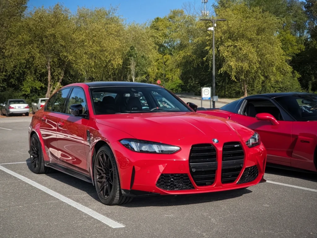 Red BMW M3 parked in a lot with trees and other cars in the background under clear sky