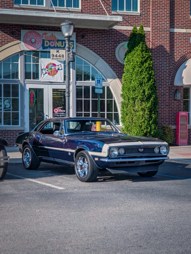 Blue Chevrolet Camaro SS parked in front of a brick building with Tasty Donuts signage