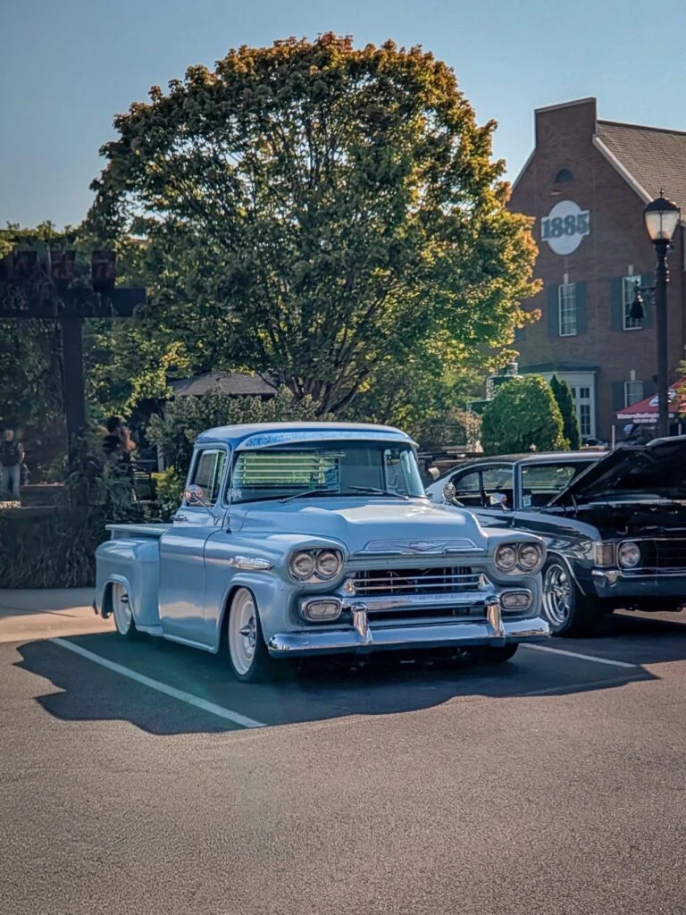 Light blue Chevrolet Apache pickup truck parked in a lot with other cars and trees in the background