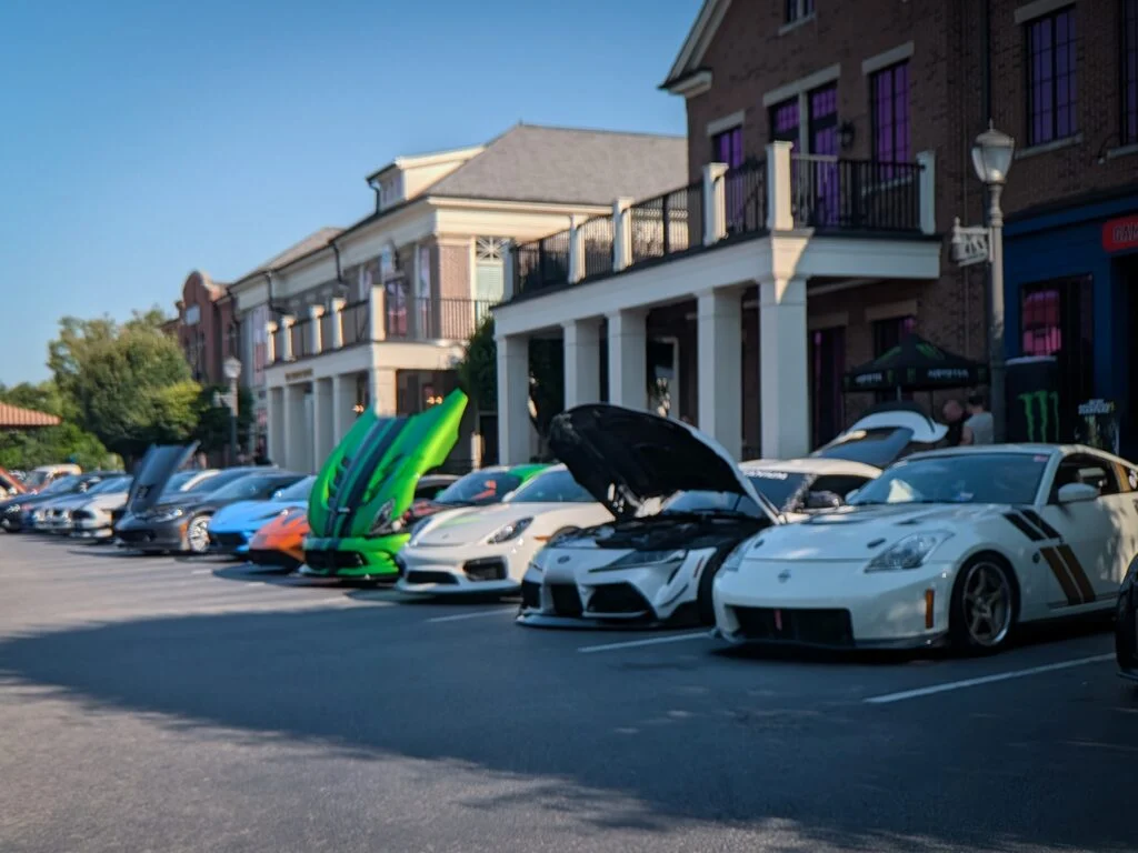 Chevrolet Corvette, Lamborghini Huracan, Dodge Viper, Porsche Cayman parked on an urban street during a car meet on a clear day.