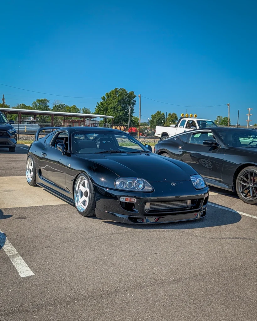 Black Toyota Supra parked at an outdoor car event under clear sky
