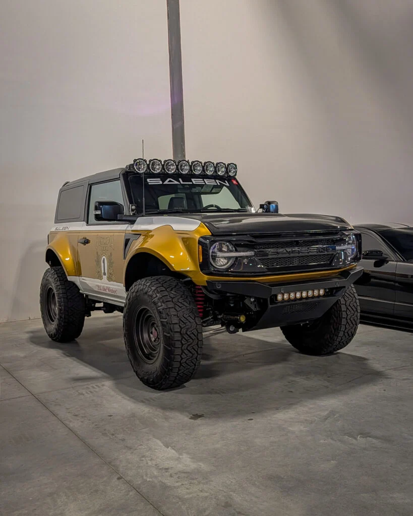 White and gold Saleen Ford Bronco with off-road tires and roof-mounted lights